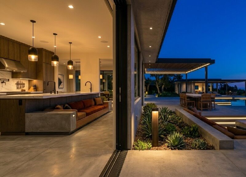 Detail shot of hidden landscape audio and synchronized circadian path lighting at the threshold of a modern luxury estate.